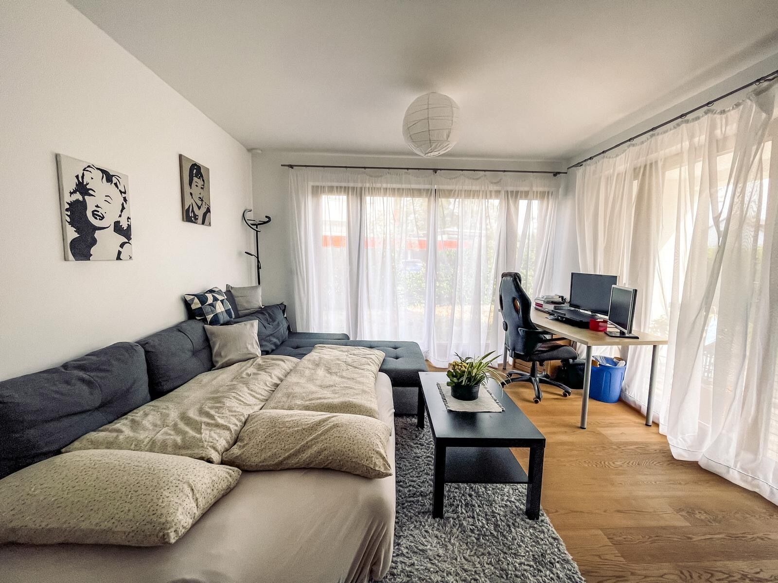 A modern living room with a sofa, a coffee table, and a desk with a computer.