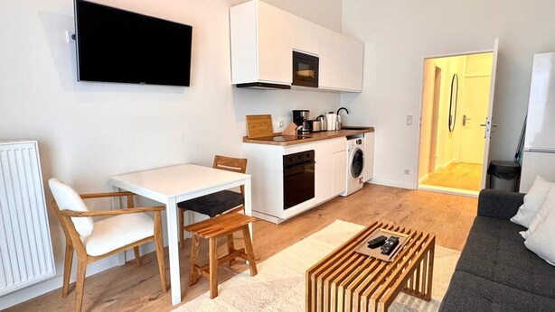 Een ruimtelijk ingerichte leefruimte met kitchenette, een eethoek en een zithoek.
