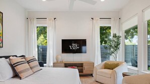 Un dormitorio moderno con cama, televisor, escritorio y silla.
