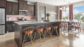 A modern kitchen with dark wood cabinets, a granite countertop, and gold bar stools.