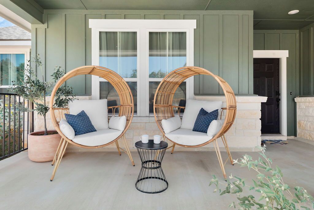 Un balcon avec deux fauteuils en osier, une petite table ronde et une plante en pot.