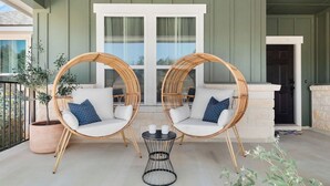 A balcony with two wicker chairs, a small round table, and a potted plant.