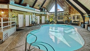 An indoor swimming pool with a clear water surface, surrounded by lounge chairs and a wooden interior. - Château Rouge 213 ~ Grizzly Peak Getaway (Red Lodge)