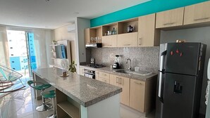 A modern kitchen with granite countertops, a black refrigerator, and a built-in oven.