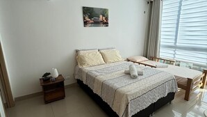 A bedroom with a bed, bedside table, and a window with curtains.