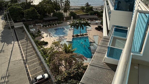 A high-rise hotel with a rooftop pool overlooking a beach and the ocean.