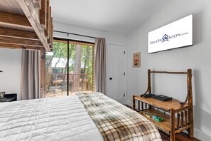 Un dormitorio con una cama grande, un banco de madera, un ventanal corredizo a un balcón y un cartel de RENTBRANSON.COM.