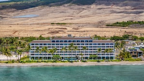 Un hotel de varios pisos, con vista al mar y montañas al fondo.