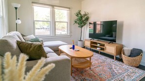 Ett modernt vardagsrum med en soffa, ett soffbord, en tv och dekorativa växter.