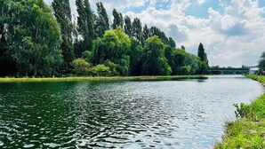 A river with a grassy bank and trees. - Quiet & spacious apartment - Secure bicycle garage - Fast WiFi (Saint-Quentin)
