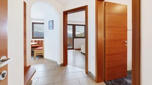 A hallway with a wooden door, a bench, and a view of a balcony. - Apartment 'Adlerhorst' with Mountain View, Shared Garden and Wi-Fi (Lagundo)