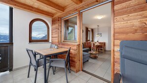 A wooden interior with a dining area, a sofa, and a view of the mountains. - Apartment 'Adlerhorst' with Mountain View, Shared Garden and Wi-Fi (Lagundo)