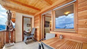 A wooden balcony with a table and chairs, a view of mountains, and a door leading to an interior space. - Apartment 'Schwalbennest' with Mountain View, Shared Garden and Wi-Fi (Lagundo)