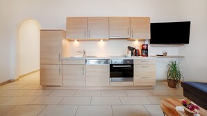A modern kitchen with built-in appliances, a flat-screen TV, and a potted plant. - Apartment 'Storchennest' with Mountain View, Shared Garden and Wi-Fi (Lagundo)