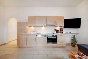 Una cocina moderna con electrodomésticos integrados, un televisor de pantalla plana y una planta en maceta.