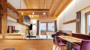 A modern kitchen with wooden beams, a central island, and bar stools. - Apartment 'Bartgeier' with Mountain View, Shared Garden and Wi-Fi (Lagundo)