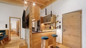 Een moderne keuken met houten keukenkastjes, een inbouwoven en een bar met krukken.