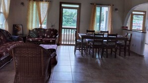 Un amplio espacio de estar con una mesa de comedor y sillas, un sofá y una silla de mimbre.