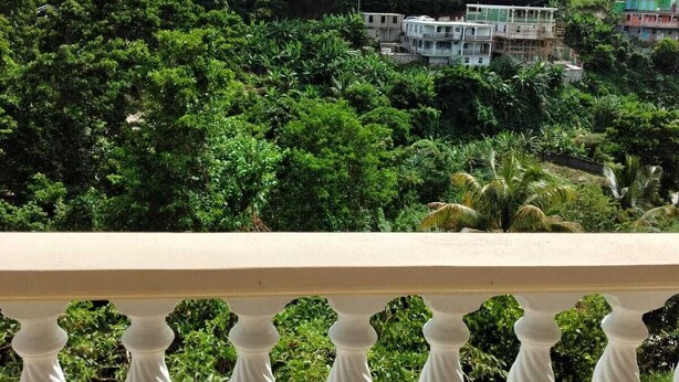 Un balcón con vistas a un paisaje verde exuberante y un edificio de varios pisos.