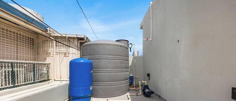 A narrow alley with water tanks and a blue gas cylinder.