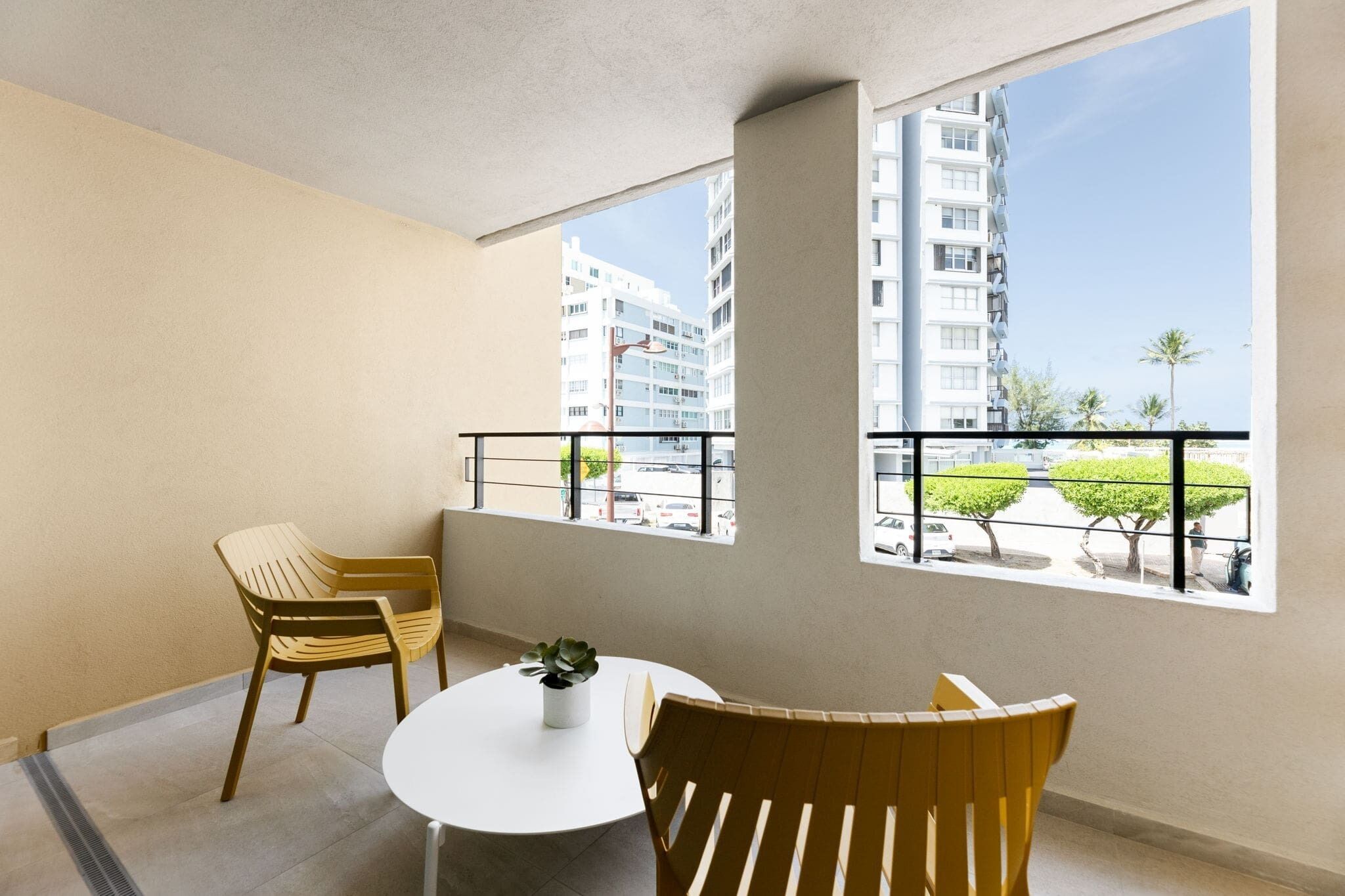 Un balcon avec deux chaises, une petite table et un pot de fleurs.
