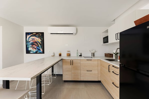 Une cuisine moderne avec un plan de travail en bois, un réfrigérateur noir et un four à micro-ondes.