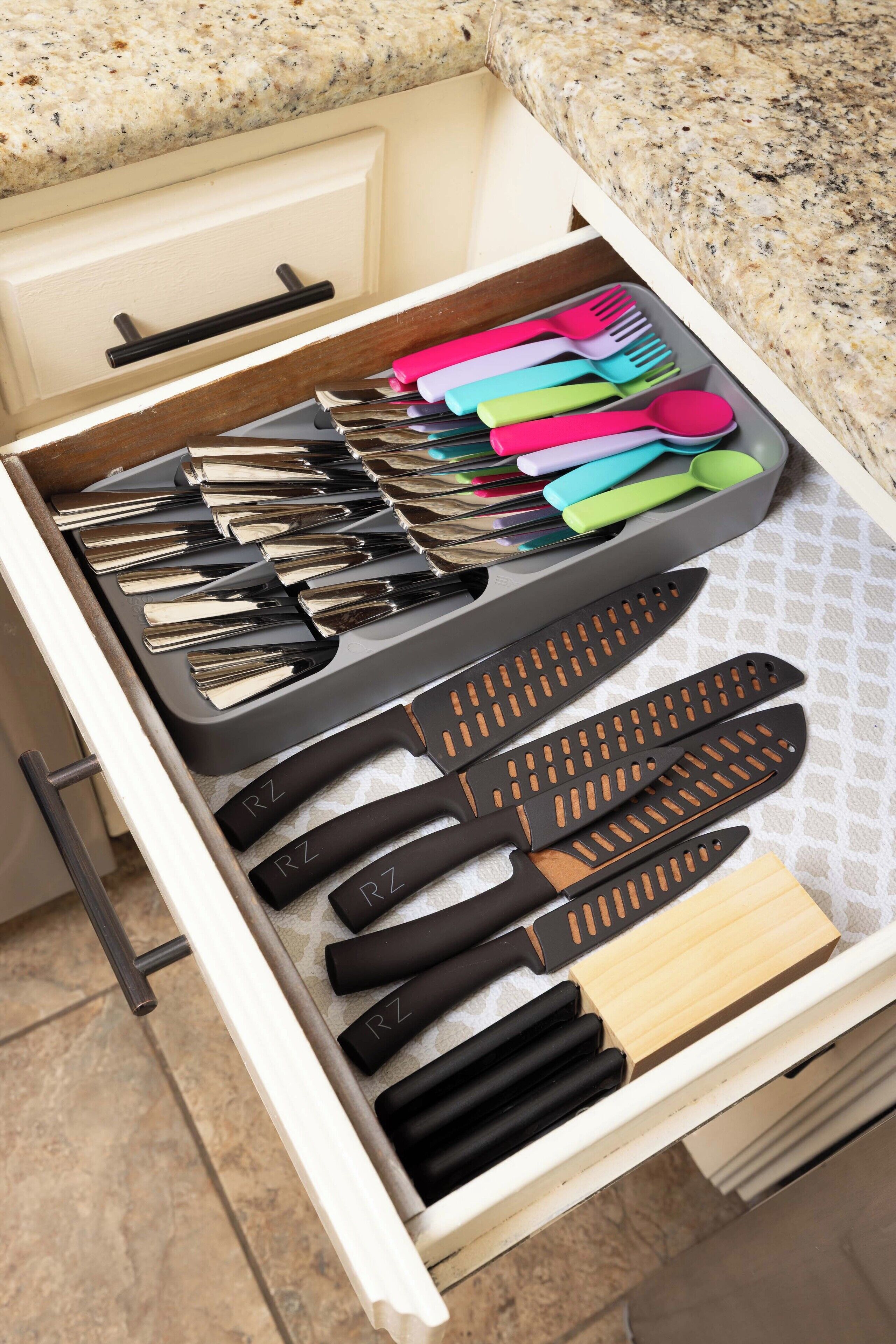 A drawer with various kitchen utensils including knives, spoons, and forks.