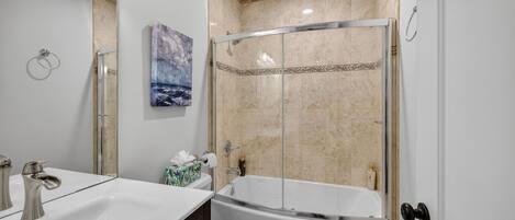 Un baño moderno con ducha envuelta en vidrio, bañera independiente y tocador con doble lavabo.