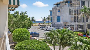 A modern building with a parking area, palm trees, and a view of the ocean. - Daisy Townhouse  Steps from The Beach (Pompano Beach)