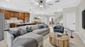 A modern living room with a sectional sofa, a coffee table, and a ceiling fan. - Daisy Townhouse  Steps from The Beach (Pompano Beach)