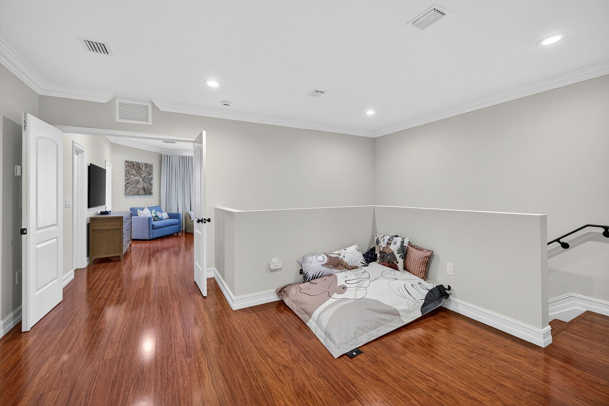 A bedroom with a large bed, a blue sofa, and a hallway leading to another room.