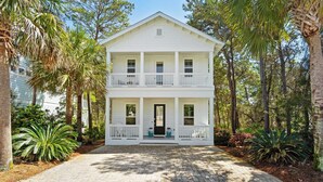 A two-story white house with a front porch, surrounded by trees and plants. - 2 Homes in Inlet Beach by Avantstay Dock+lake Access, Saltwater Pool, Close to the Beach (Panama City Beach)