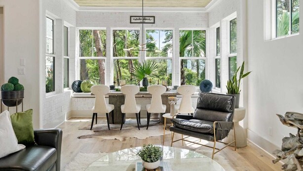 A bright, spacious room with large windows, a dining area with white chairs, a leather sofa, and a glass coffee table. - 2 Homes in Inlet Beach by Avantstay Dock+lake Access, Saltwater Pool, Close to the Beach (Panama City Beach)