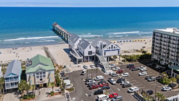 A coastal hotel with a pier extending into the ocean, a parking lot, and a beach area. - Peaceful 2-bedroom condo at the beach with a water view! (Surfside Beach)