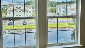 A room with two large windows, a small round table, and a potted plant. - Peaceful 2-bedroom condo at the beach with a water view! (Surfside Beach)