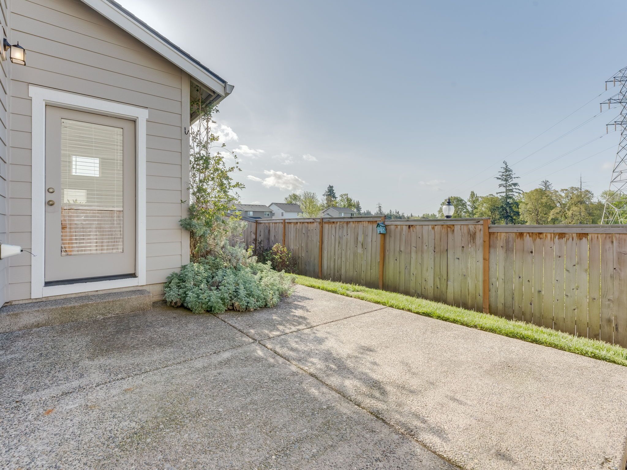 A residential property with a wooden fence, a front door, and a small garden area.
