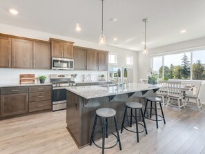 Una cocina moderna con armarios de madera, electrodomésticos de acero inoxidable y una isla grande con taburetes de bar.
