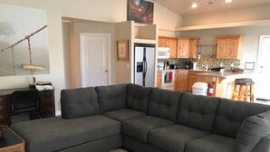 Ein Wohnzimmer mit Ecksofa, einem kleinen Holztisch und einem gemusterten Teppich.