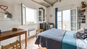 A bedroom with a bed, a desk, a chair, a dresser, and a wardrobe. There is a window with a view of the beach. - Gorgeous home in Saint-Pierre-d'Oléron with WiFi (Saint-Pierre-d'Oléron)