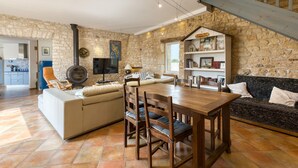 A cozy living area with a stone wall, a fireplace, a dining table with chairs, a sofa, and a bookshelf. - Gorgeous home in Saint-Pierre-d'Oléron with WiFi (Saint-Pierre-d'Oléron)