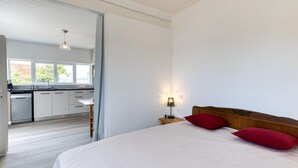 A bedroom with a bed, a nightstand, and a lamp. There is a view of a kitchen with a dishwasher and cabinets. - Pet friendly home in Saint-Pierre-d'Oléron (Saint-Pierre-d'Oléron)