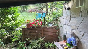 Un patio cubierto con muro de piedra, una estatua de Buda y diversas plantas en macetas.