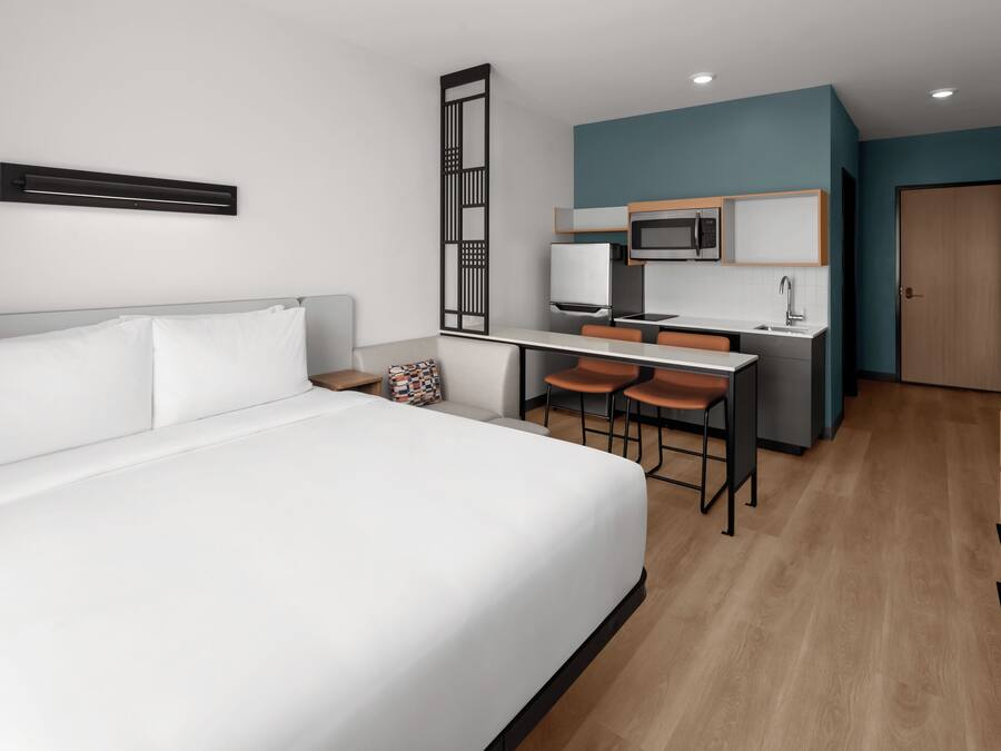 Ein Hotelzimmer mit einem Bett, einem Schreibtisch mit zwei Stühlen, einer Mikrowelle und einem Waschbecken.