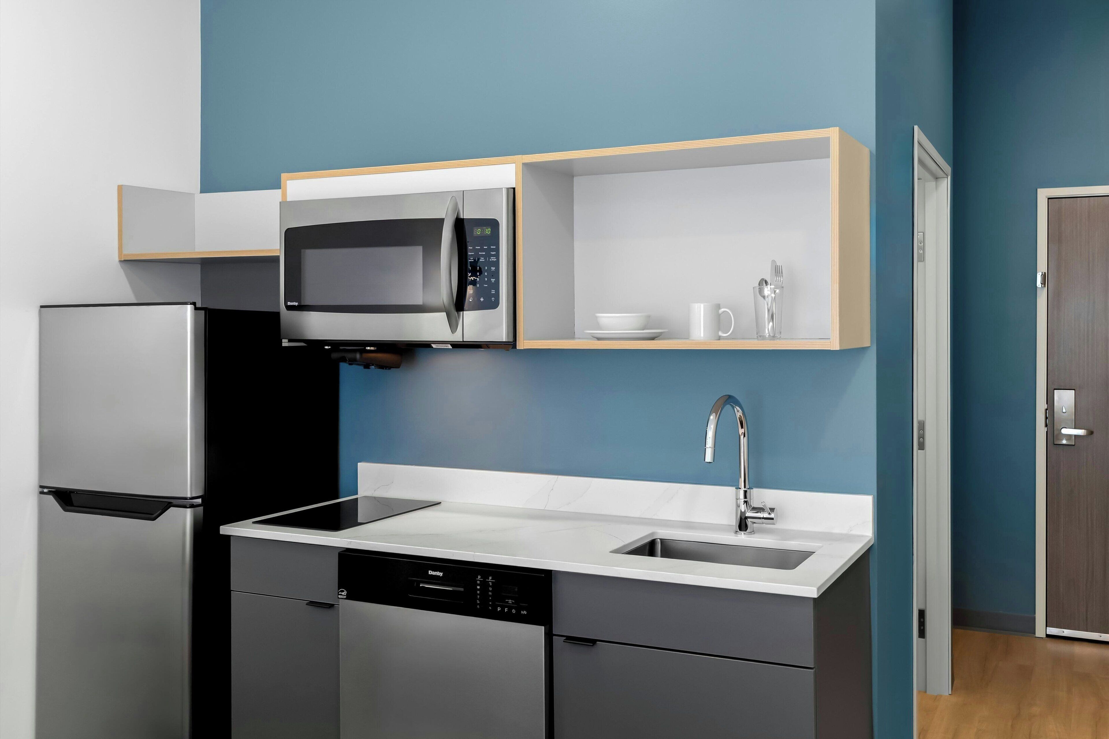 A modern kitchen with a stainless steel refrigerator, a built-in microwave, a dishwasher, and a sink.