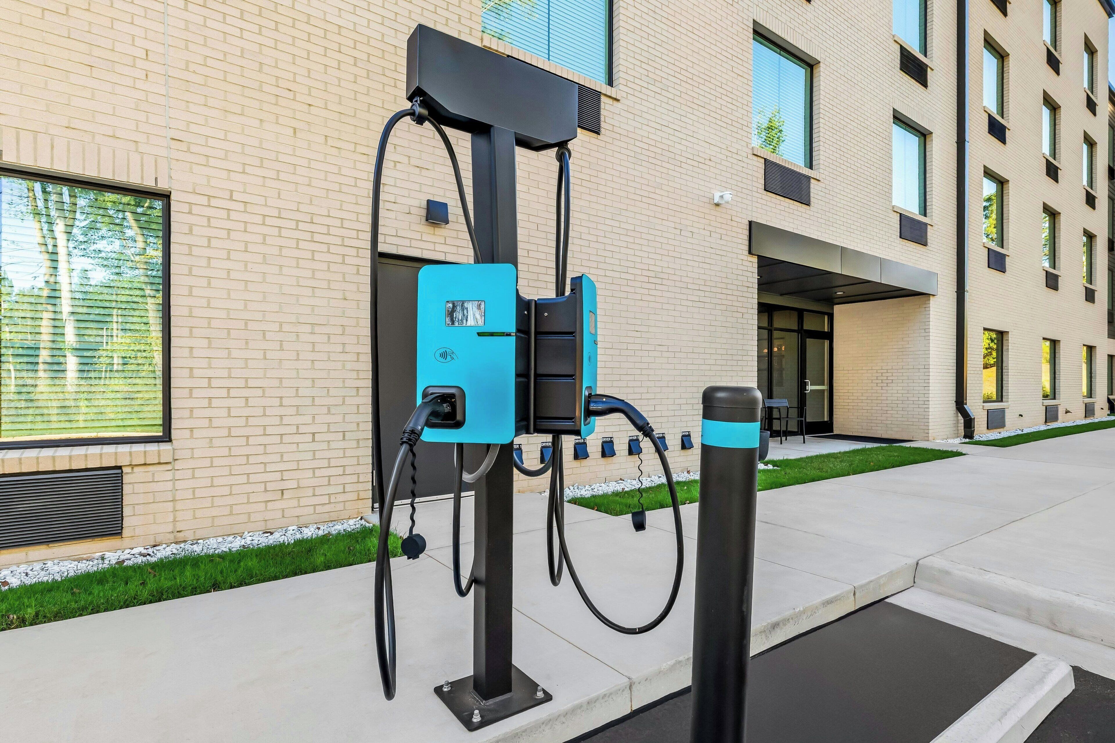 Eine Ladestation für Elektroautos vor einem modernen Gebäude mit Ziegel Fassade und großen Fenstern.