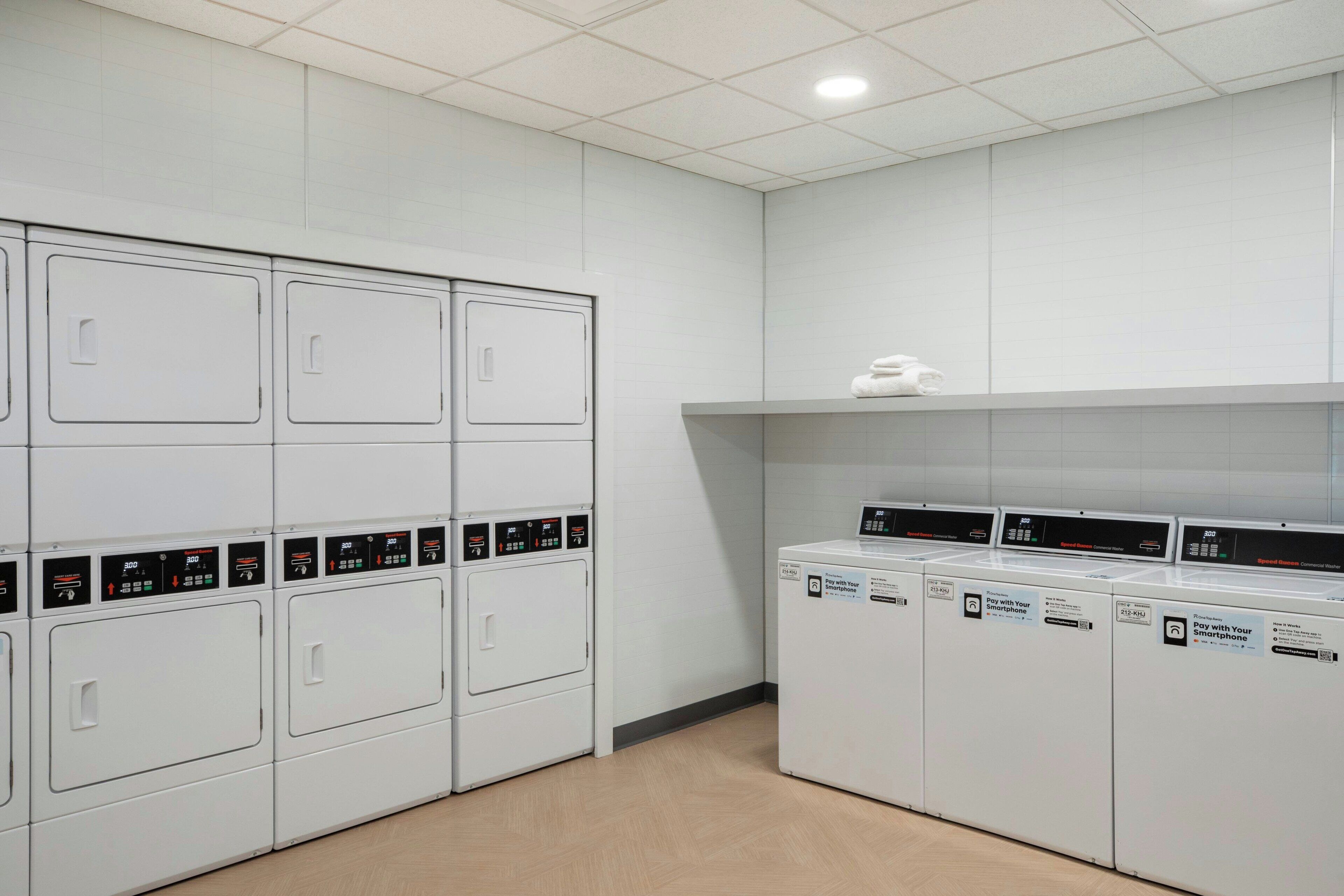 A laundry facility with multiple washing machines and dryers, arranged in rows.