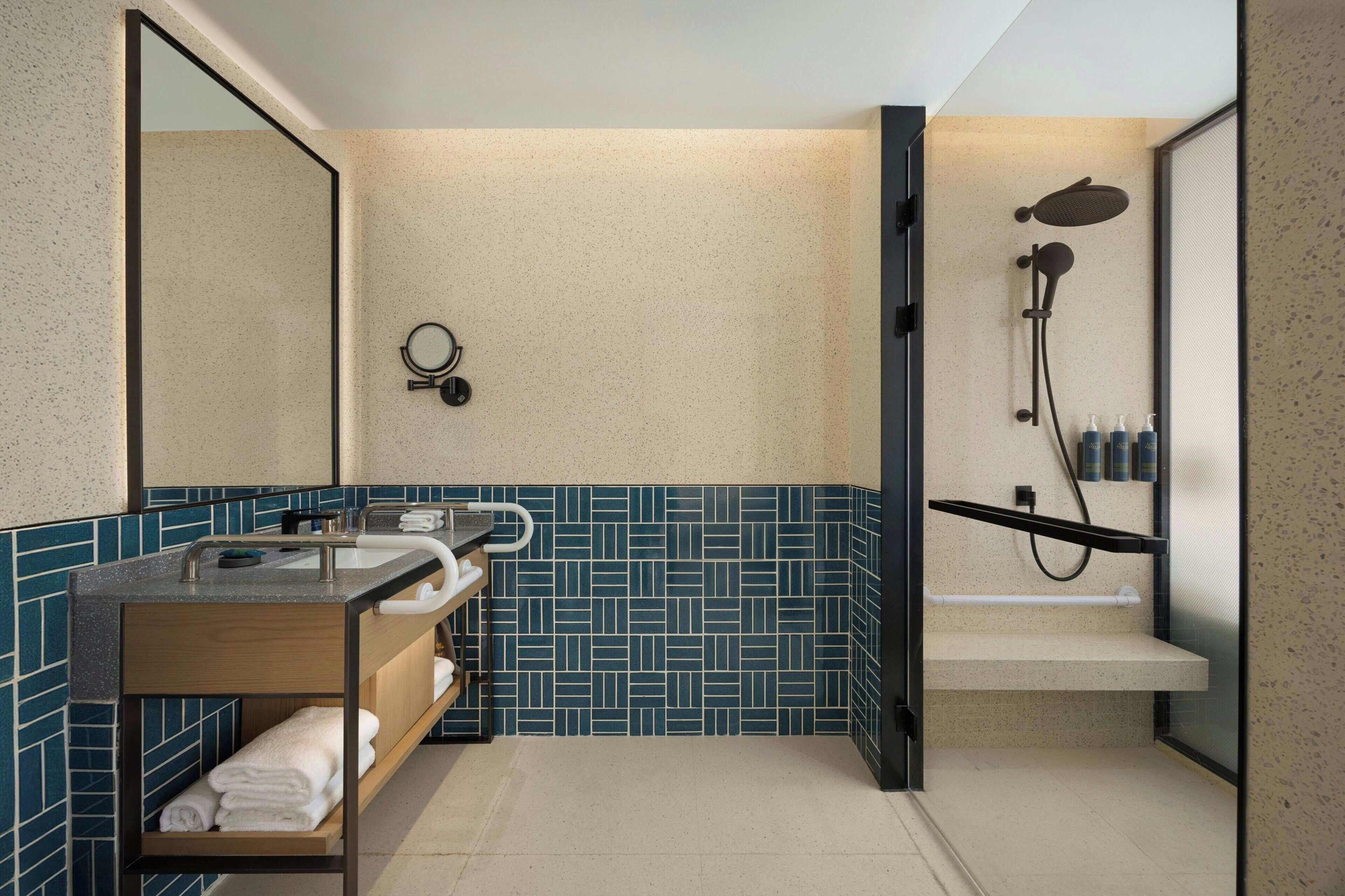 A modern bathroom with a dual sink vanity, a large mirror, a shower enclosure, and a towel rack.