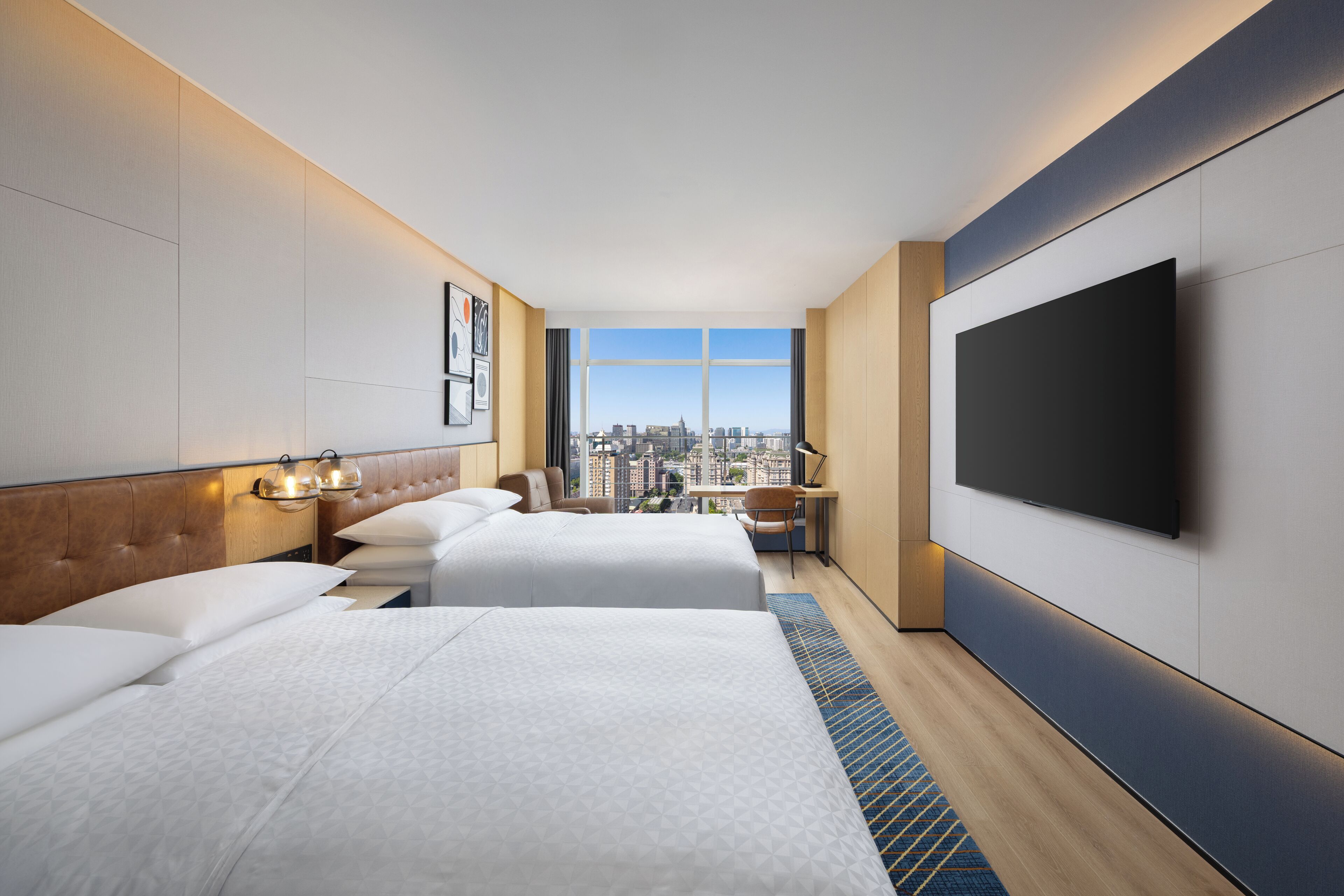 A modern hotel room with two beds, a flat-screen TV, and a city view.