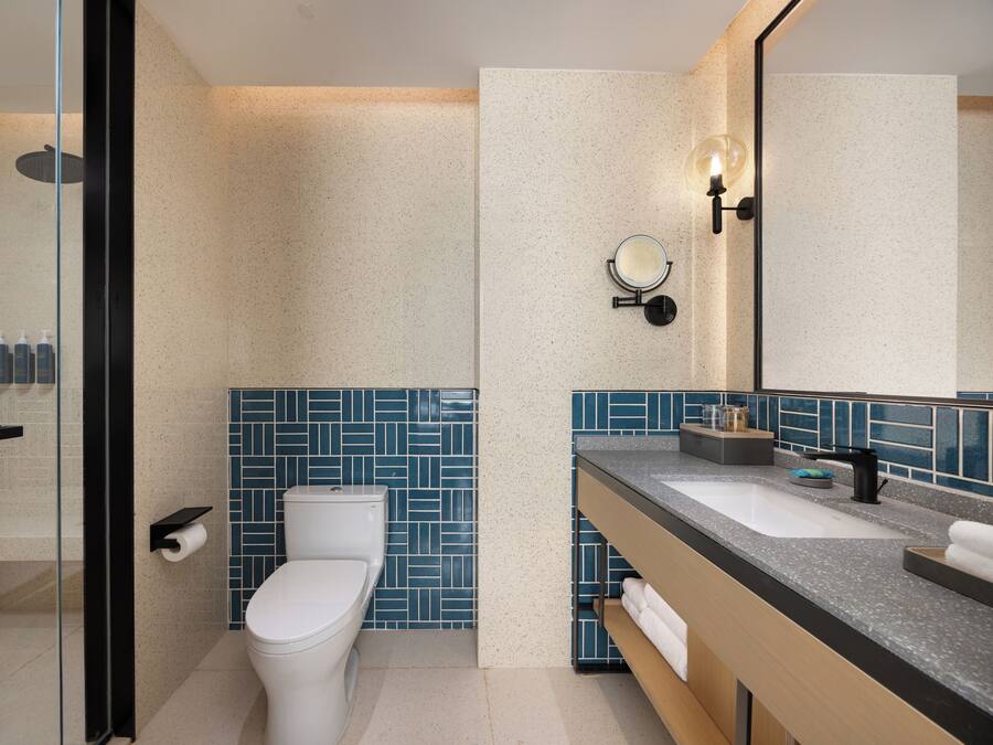 A modern bathroom with a glass shower enclosure, a white toilet, and a vanity with a sink and mirror.