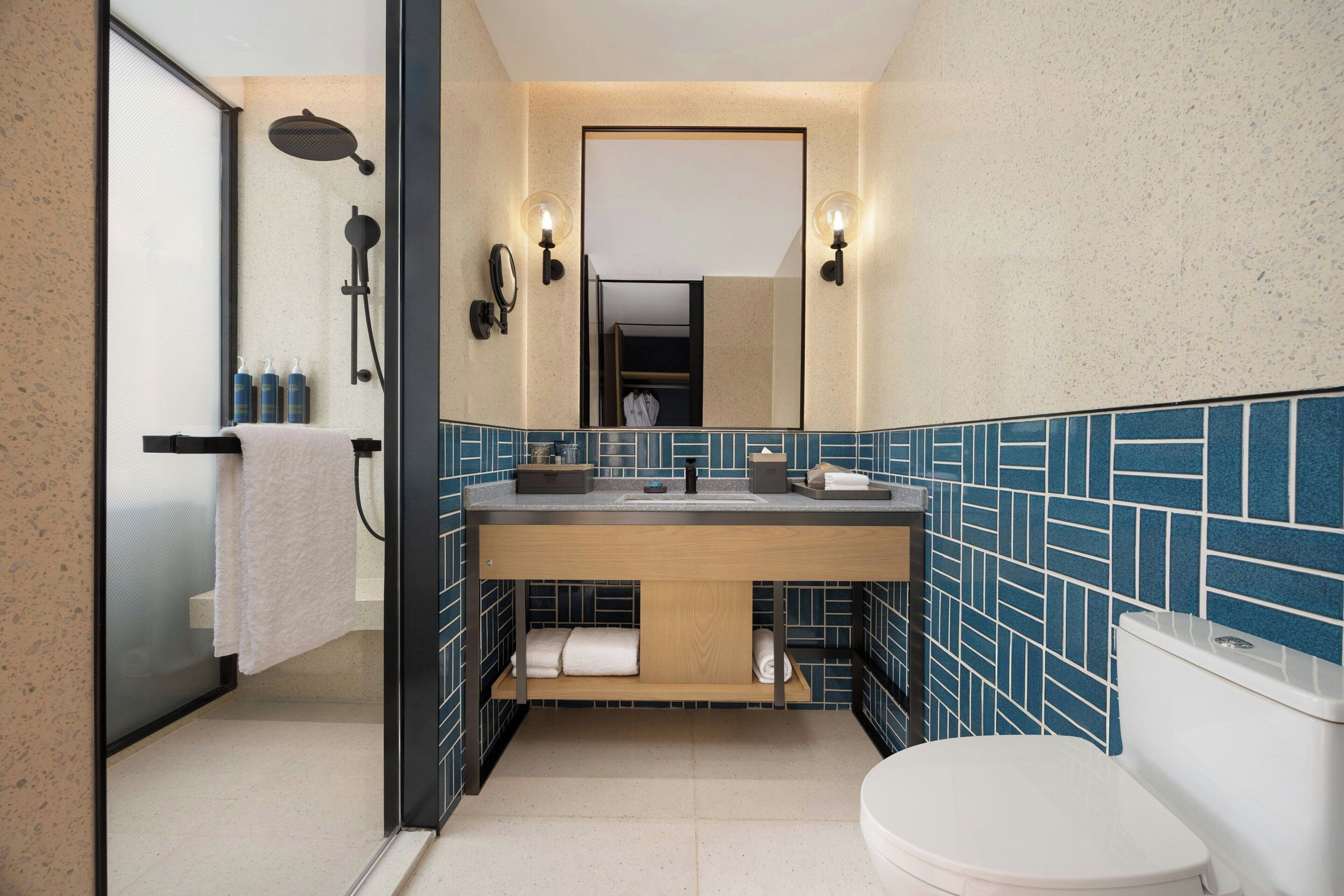 A modern bathroom with a shower, a sink with a mirror, and a toilet.